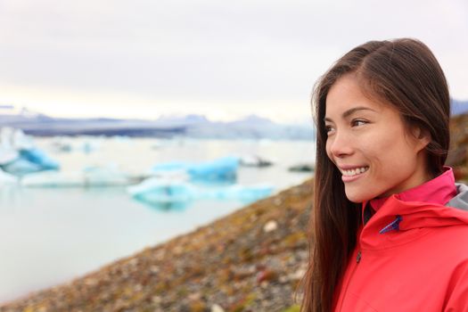 Woman at glacier lagoon on Iceland. Happy tourist woman looking enjoying view of Jokulsarlon glacial lake. Smiling woman in beautiful Icelandic nature landscape looking at iceberg.