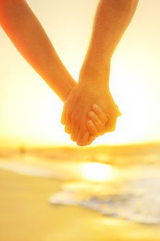Couple in love holding hands - happy relationship. Closeup of male and female arms together at beach sunset during holidays tropical vacations.
