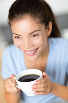 Asian chinese woman drinking coffee or black tea. Portrait of young adult student smiling holding mug at cafe or home in the morning as part of a healthy breakfast.