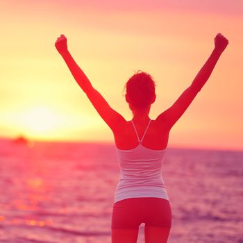 Life achievement - happy woman arms up in success. Back view of female silhouette proud of reaching her health goal arms raised looking at ocean and sunset. Happiness winning goal concept.