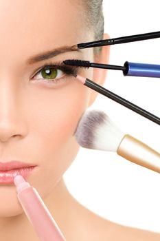 Makeup beauty transformation concept face makeover - Asian woman with many brushes against one side of the face putting mascara, blush and lip gloss