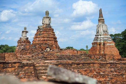 Old pagoda and ruined Buddha statue in Chaiwatthanaram temple. Ayutthaya, Thailand.