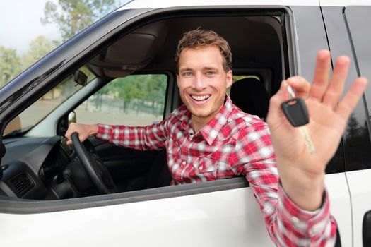 New cars concept - man driving car showing car keys happy looking at camera. Caucasian male driver on road trip using car rental.