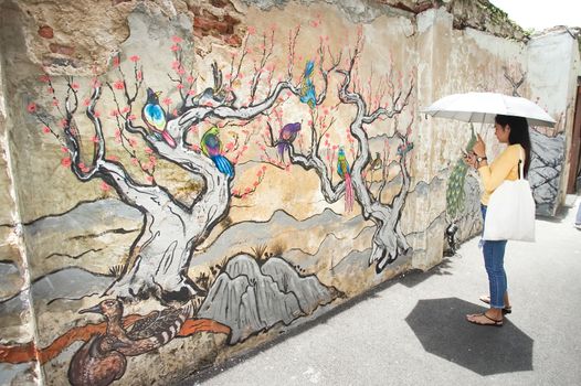 Bangkok, Thailand - September 2, 2018: Woman in front of the Chinese style mural in Lhong 1919. The old pier in the past became to a new attraction in Bangkok, Thailand.