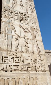 Egyptian hieroglyphic carvings and paintings on wall of the ancient temple at Medinat Habu in Luxor