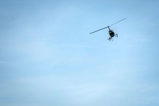 Helicopter silhouette on a light blue sky background