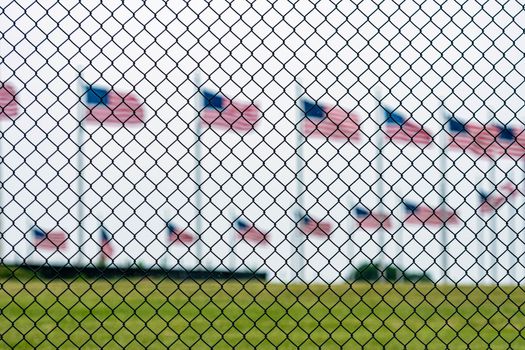 American flags at the Washington Memorial behind the wire fence. Focus on the wire fence.