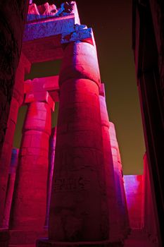 Columns in the ancient egyptian temple of Karnak at Luxor with hieroglyphic carvings lit up during the night sound and light show