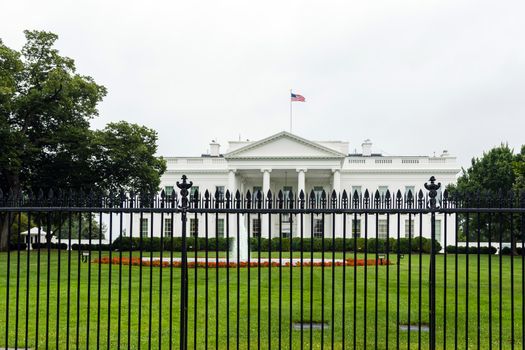 The east side of the White House with fountain, iron fence and red flowers in the foreground.