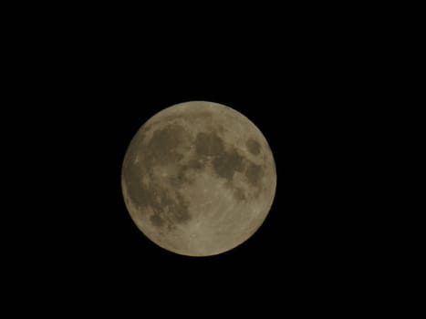 Genova, Italy - 07/05/2020: An amazing photography of the full moon over the city of Genova by night with a great clear and blue sky in the background and some stars.