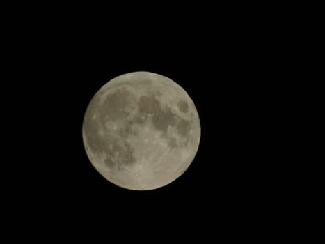 Genova, Italy - 07/05/2020: An amazing photography of the full moon over the city of Genova by night with a great clear and blue sky in the background and some stars.