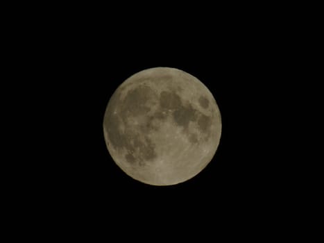 Genova, Italy - 07/05/2020: An amazing photography of the full moon over the city of Genova by night with a great clear and blue sky in the background and some stars.