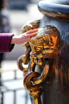 Tourists are lucky to touch the Shinning Chinese brass lion-head large-bowl handle at The Forbidden City in Beijing, China