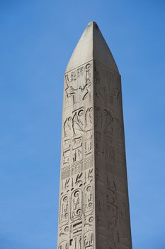 Large ancient obelisk with egyptian hieroglyphics at Karnak temple in Luxor against a blue sky background