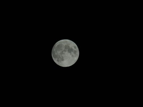 Genova, Italy - 07/05/2020: An amazing photography of the full moon over the city of Genova by night with a great clear and blue sky in the background and some stars.