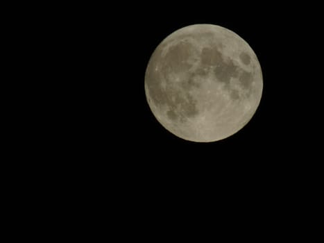 Genova, Italy - 07/05/2020: An amazing photography of the full moon over the city of Genova by night with a great clear and blue sky in the background and some stars.