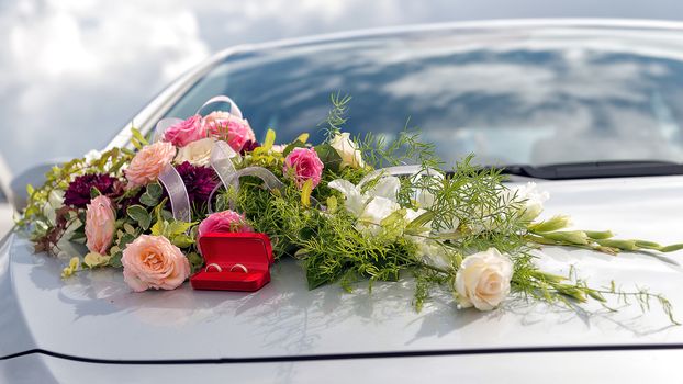 Flower decoration and a ring set on gray wedding car bonnet.