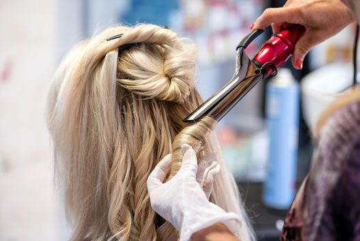 Hairdressers hands with a circle of scissors hair styled blonde woman.