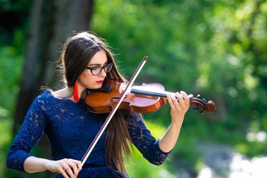 Young woman playing the violin at park. Shallow depth of field.