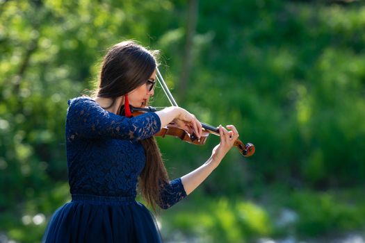 Young woman playing the violin at park. Shallow depth of field.