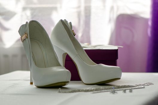 Standing on a white tablecloth white bridal shoes.