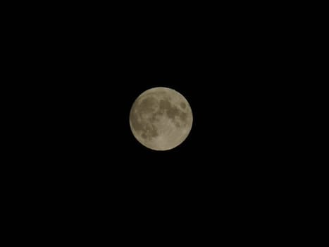 Genova, Italy - 07/05/2020: An amazing photography of the full moon over the city of Genova by night with a great clear and blue sky in the background and some stars.