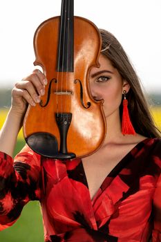 Portrait of a positive young woman. Part of the face is covered by the neck of the violin.