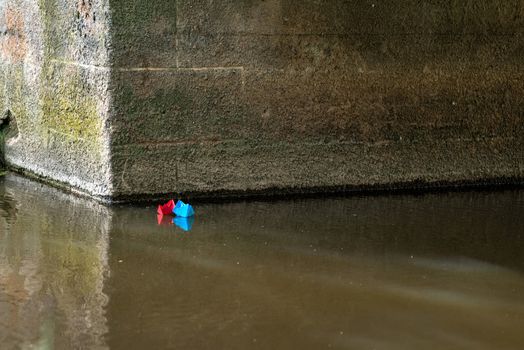 Red and blue paper boat is flying on the river. Wedding concept.