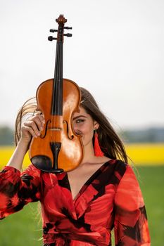 Portrait of a positive young woman. Part of the face is covered by the neck of the violin.