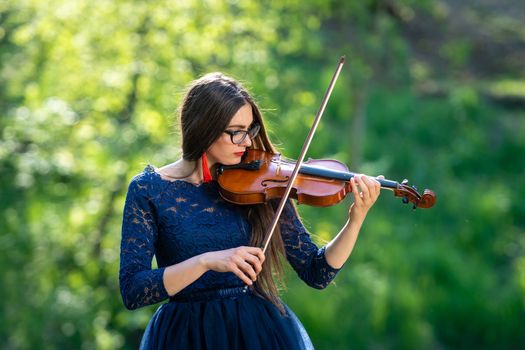 Young woman playing the violin at park. Shallow depth of field.