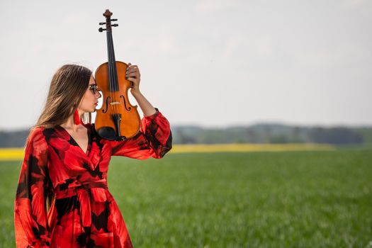 Portrait of a positive young woman. Part of the face is covered by the neck of the violin.