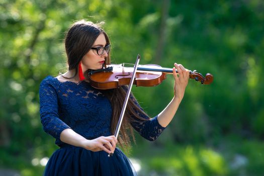 Young woman playing the violin at park. Shallow depth of field.