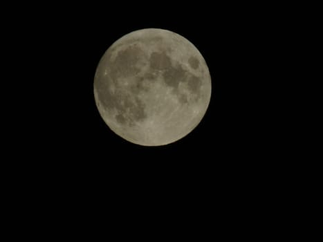 Genova, Italy - 07/05/2020: An amazing photography of the full moon over the city of Genova by night with a great clear and blue sky in the background and some stars.