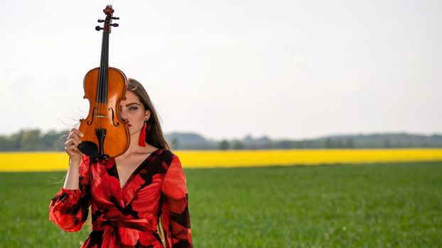Portrait of a positive young woman. Part of the face is covered by the neck of the violin.