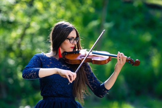 Young woman playing the violin at park. Shallow depth of field.