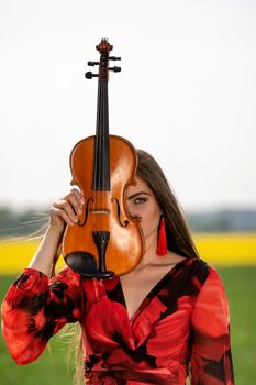 Portrait of a positive young woman. Part of the face is covered by the neck of the violin.