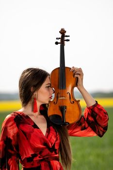 Portrait of a positive young woman. Part of the face is covered by the neck of the violin.