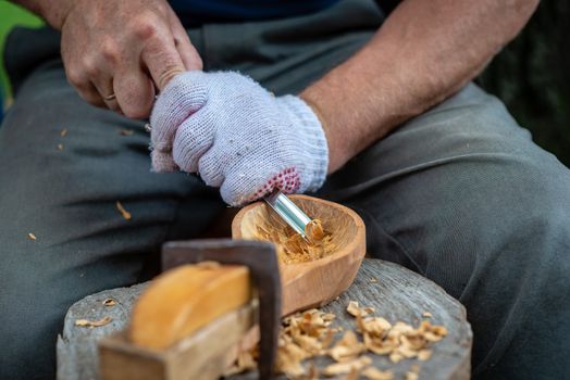 Craftsman demonstrates the process of making wooden spoons handmade using tools. National crafts concept.