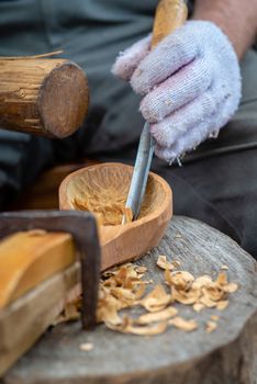 Craftsman demonstrates the process of making wooden spoons handmade using tools. National crafts concept.