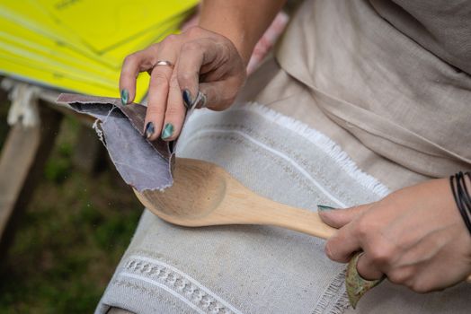 the woman makes traditional handcraft wooden spoon. - Image