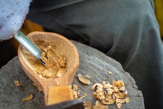 Craftsman demonstrates the process of making wooden spoons handmade using tools. National crafts concept.