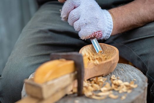 Craftsman demonstrates the process of making wooden spoons handmade using tools. National crafts concept.