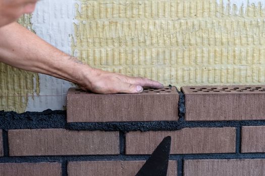 Bricklayer worker installing bricks on construction site.