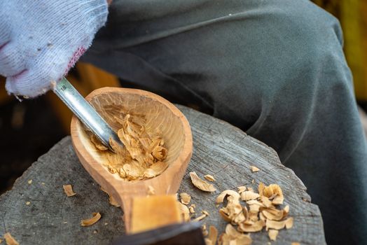 Craftsman demonstrates the process of making wooden spoons handmade using tools. National crafts concept.