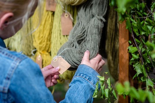 Traditional latvian craft market. Woman looking for yarn. - image