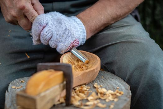 Craftsman demonstrates the process of making wooden spoons handmade using tools. National crafts concept.