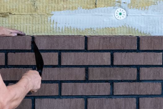 Bricklayer worker installing bricks on construction site.