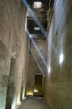 Beams of sunlight across a corridor inside an ancient egyptian temple with hieroglyphic carvings