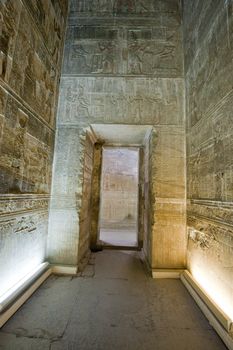 Corridor through an arched doorway in an ancient egyptian temple with hieroglyphic carvings
