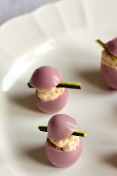 deviled quail eggs with cream cheese, dyed with beet juice, on withe plate